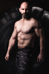 Senior crossfit male athlete posing in front of a Tire