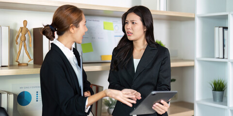 Problem Solving in Office. Two women discussing challenges while reviewing a tablet.