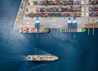 Aerial top down view of a large container cargo ship terminal with loading activity and vessel traffic