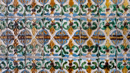 Historic Mudejar ceramic wall tiles arranged in a geometric and floral repeat pattern with glazed surfaces, dating back to the 15th century inside the Royal Alcazar palace, Seville, Andalusia, Spain