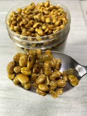 Delicious fried soybean snack. fried soybeans in a plastic jar and on a spoon.