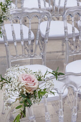 Elegant outdoor wedding ceremony setup featuring acrylic chairs with white cushions arranged in...