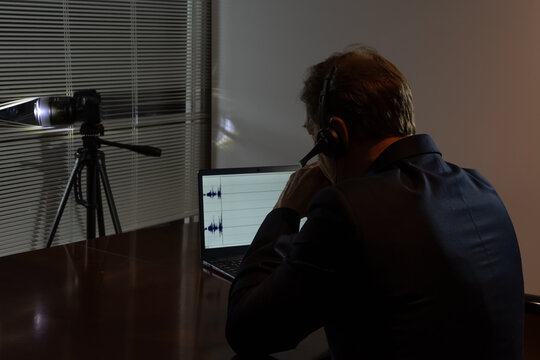 An undercover agent works at night: camera, headphones, audio recording on a laptop screen.