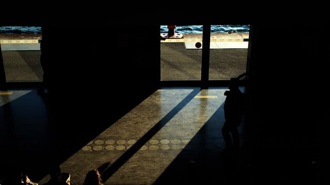 Silhouette of a walking man inside a ferryboat pier terminal in super slow motion