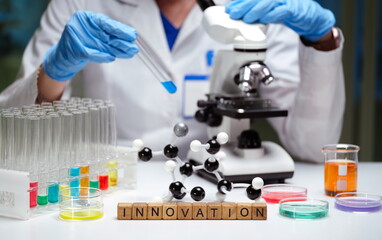 A skilled scientist conducts innovative research in a lab using a microscope and chemicals to make...