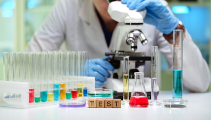 Fototapeta premium A diligent researcher examines samples under a microscope, surrounded by test tubes for ongoing experiments