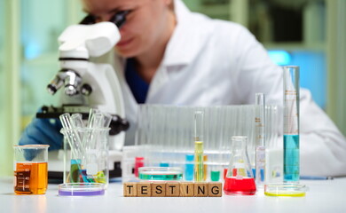 Fototapeta premium A researcher examines samples using a microscope, surrounded by test tubes and reagents for scientific testing.