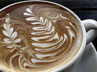 Close up of elaborate swirled milk forth art on a cappuccino.