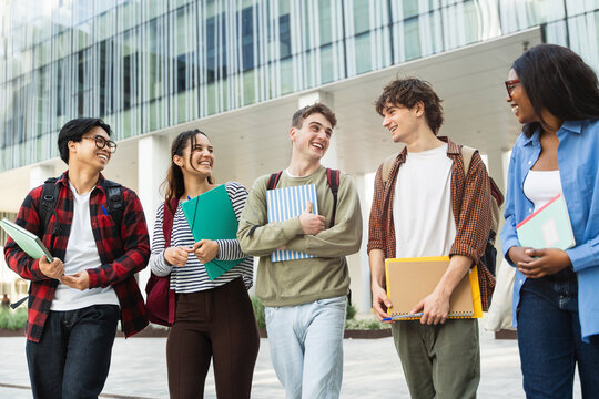 Happy students walking on university campus, chatting and laughing together after classes 