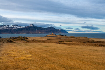 Fototapeta premium Icelandic Coastal Landscape with Lighthouse and Snow-Capped Mountains