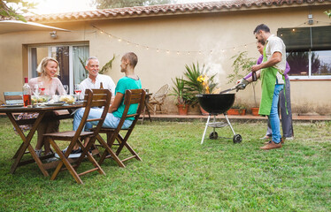 Friends enjoying summer party at home garden cooking barbecue and having fun together