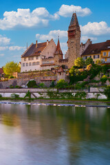 Fototapeta premium Historic castle overlooks tranquil river under a bright blue sky in the late afternoon