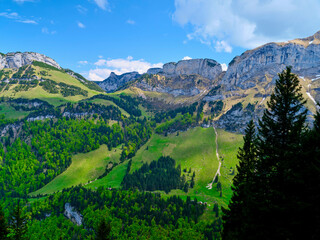 Obraz premium Mountains and lush greenery create a serene landscape under a bright blue sky in early afternoon