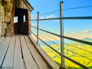 Scenic viewpoint along wooden walkway overlooking lush green valley under clear blue sky