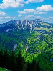 Breathtaking view of green mountains under a blue sky with fluffy clouds in the background during a sunny day