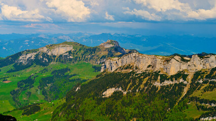 Scenic mountain landscape with rugged cliffs and lush green valleys under a partly cloudy sky