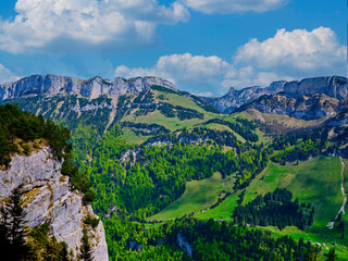 Breathtaking mountain landscape with lush green valleys and rocky cliffs under a clear blue sky