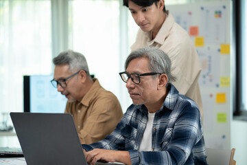 Senior men in a classroom setting engage in learning coding, with a focus on new technology and...