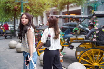 Young Asian Women Holding Hands Exploring City Street with Rickshaws in Background