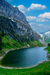 Scenic mountain lake surrounded by greenery and rocky cliffs under a bright blue sky