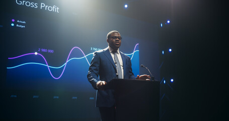 Businessman Giving a Talk at a Global Finance Summit. Audience Listening to His Insightful Talk. Speaker Showing a Presentation on Screen While Making a Motivational Speech