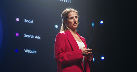 Visionary Female Public Keynote Speaker Delivering a Motivational Speech on Stage, Hosting a...
