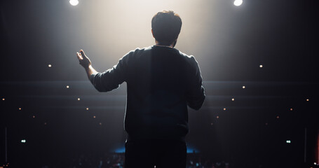 South Asian Speaker Welcoming the Audience as He Goes on Conference Stage. Businessman Standing with His Back to Camera, Dressed Casually, Speaking About Marketing at an International Business Event