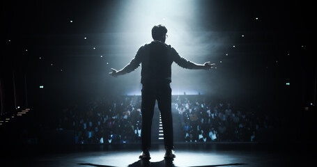 Anonymous Man Standing Under a Spotlight on Stage in Front of a Sold-Out Audience. Motivational Speaker or a Stand Up Comedian Making an Unforgettable Performance