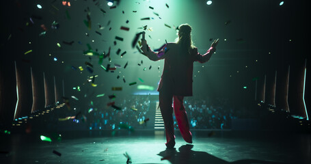 Female Speaker Walking Under a Spotlight on Stage in Front of a Big Audience. Colorful Confetti...
