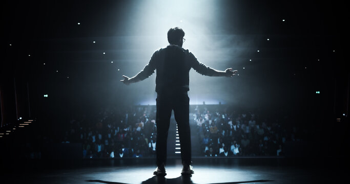Anonymous Man Standing Under a Spotlight on Stage in Front of a Sold-Out Audience. Motivational Speaker or a Stand Up Comedian Making an Unforgettable Performance