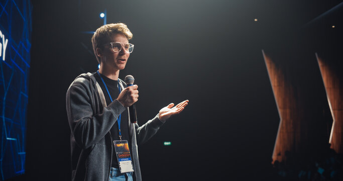 Young Speaker with Expertise in Business Development Coaching a Group of Specialists During a Presentation at an International Technology Conference. Man Dressed in Casual Clothes and Wearing Glasses