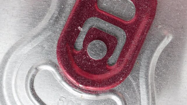 Macro Top View Of A Dusty Red Aluminum Drink Can Pull Tab Slowly Rotating. Beverage Packaging Detail. Close Up.