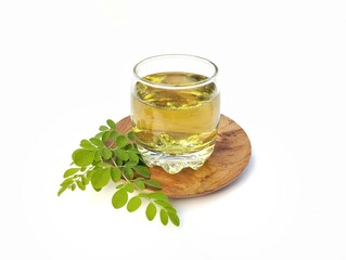 Boiled moringa leaves water in glass on white background. Healthy drink lifestyle