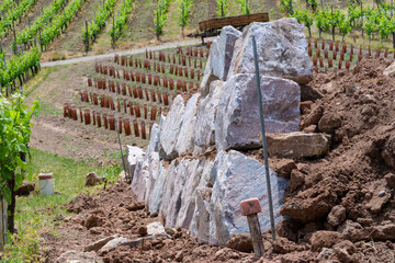 Chantier en cours : les premières pierres d'un mur de soutien dans le vignoble en terrasse sur les...