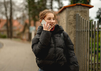 Fototapeta premium Happy Girl Talking On The Phone Against A Blurred Street Background