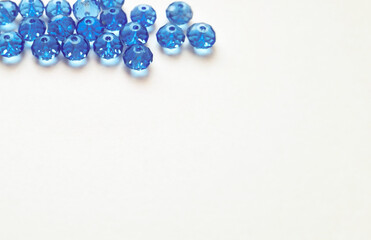 Blue crystal beads arranged in upper part of frame on white background. Jewelry materials flat lay....