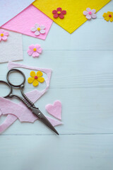 DIY greeting card crafting materials, including colorful felt flowers, scissors, glue on white wooden background, showcasing the process of creating a personalized handmade card for special occasions