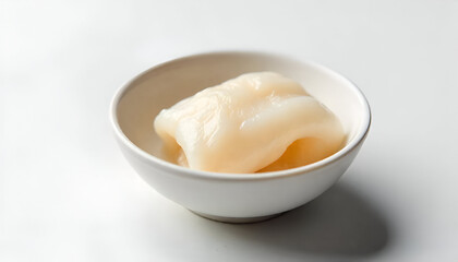 A small piece of Hákarl (fermented shark meat) placed delicately in a tiny bowl.