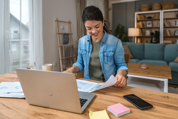 Young woman freelance worker small startup company business owner calculating tax return with data...