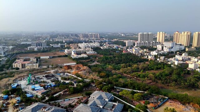 Aerial view of Chennai's urban sprawl, OMR area. Shows mixed development: modern high-rises, ongoing construction, green patches, and older structures.