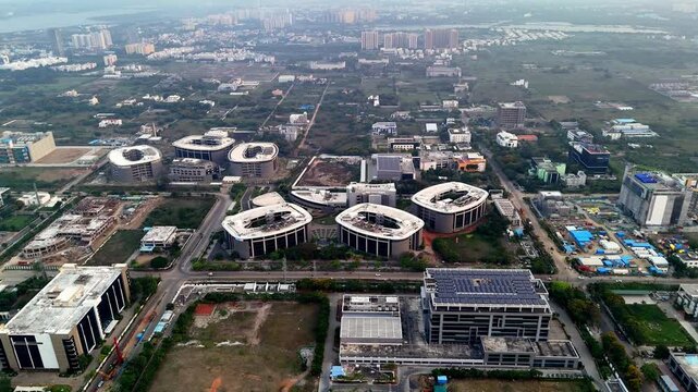 Aerial view of Infosys Chennai campus in Sholinganallur, featuring distinctive oval-shaped buildings and a solar-paneled rooftop, showcasing modern corporate architecture and green tech.