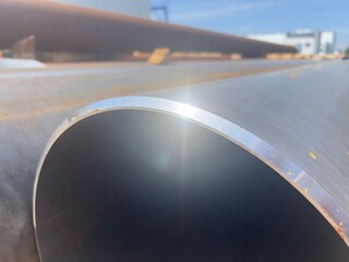 Close-up view of stacked steel tubes stored in an industrial warehouse. Ideal for themes related to...