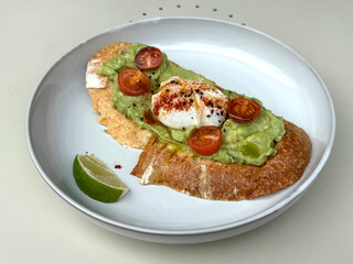 Healthy Open Sandwich with Smashed Avocado, Poached Egg, Paprika, Cherry Tomatoes, and Lime on Table. Quick Modern Snack Concept. Authentic Mobile Photo, Selective Focus, Non-AI
