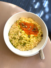 Millet Porridge with Apricot Jam, Pumpkin Seeds, and Pistachio Crumbs in a White Bowl. Healthy Carbohydrates Concept. Handmade Mobile Photo, Selective Focus, Not AI