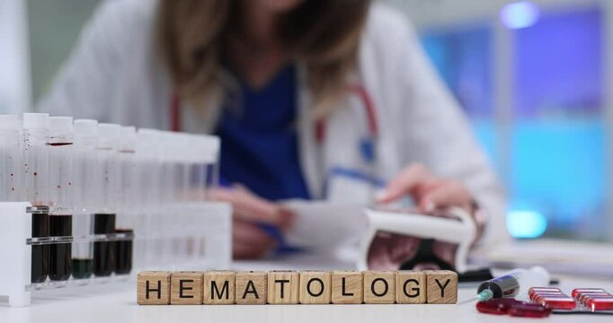 Hematologist examines ultrasound scan near wooden cubes with Hematology and blood samples in laboratory. Significance of precise medical analysis