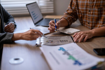 A man and a woman are sitting at a table with a laptop and a calculator