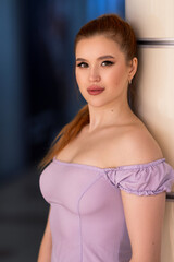 Elegant female model in lavender dress leaning against a light structure, with a composed expression and softly highlighted makeup