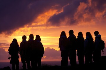 Fototapeta premium Group of hikers appreciating a breathtaking sunset view over the horizon while silhouetted against a colorful sky, symbolizing adventure and connection with nature.