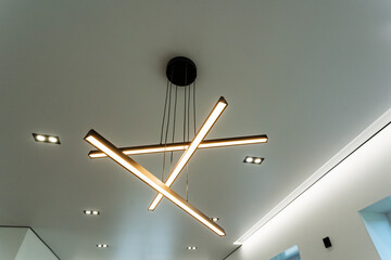 In a spacious and welldecorated room, a beautifully designed ceiling light fixture hangs gracefully...