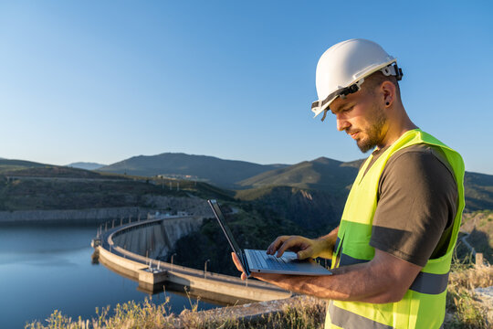 Engineer working with laptop at hydroelectric power plant dam